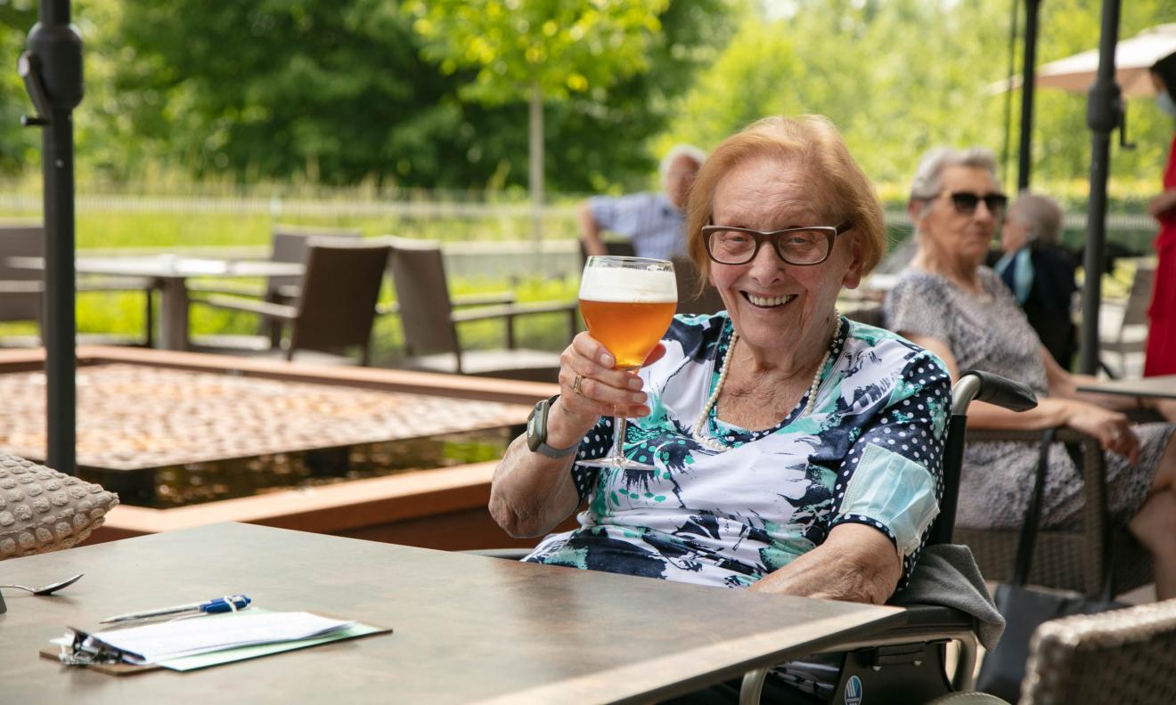 Seniorenzorg Philippus Neri vrolijke senior dame met pintje bier op terras