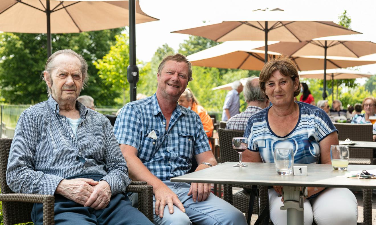 Seniorenzorg Philippus Neri familie op bezoek bij senior heer op terras buiten
