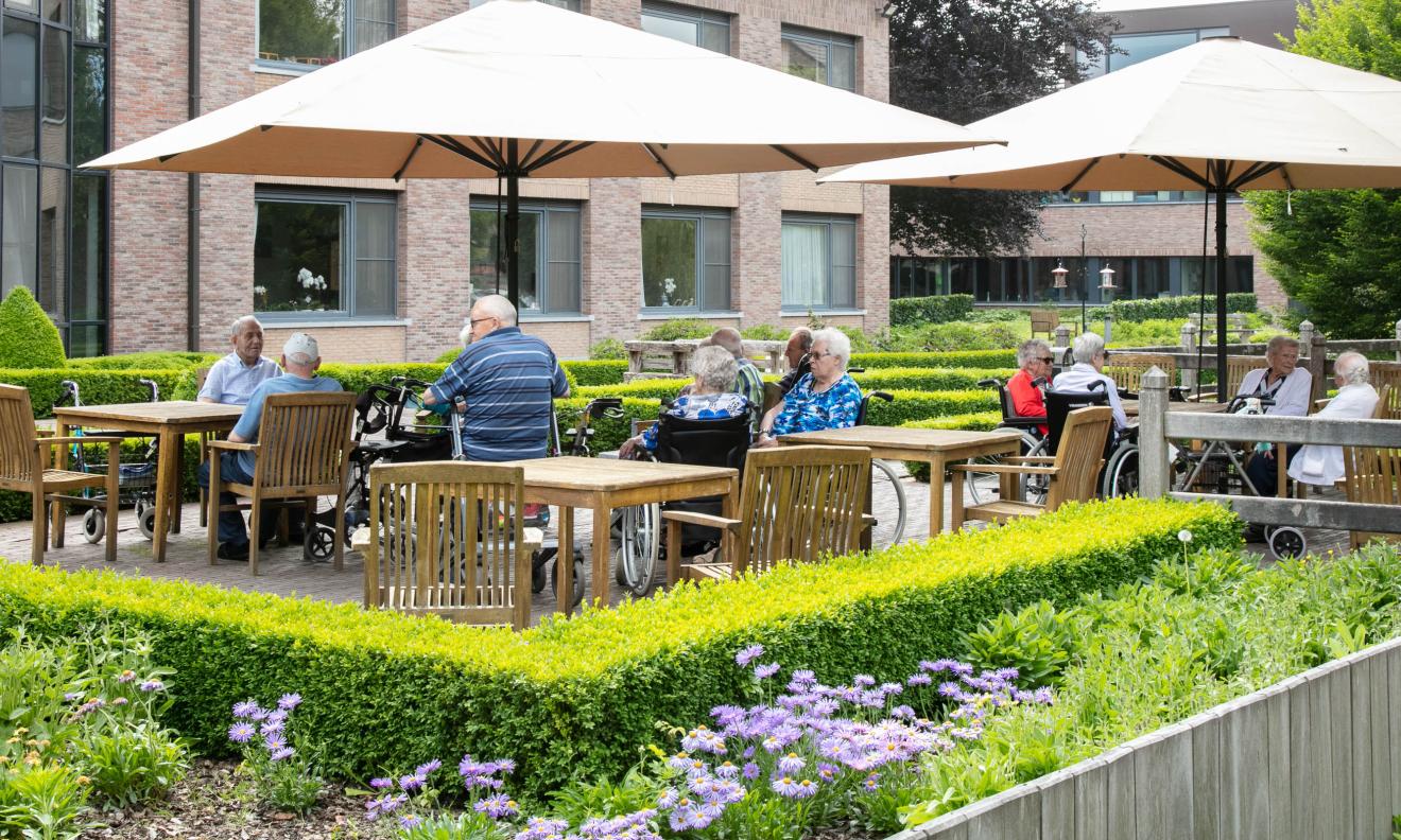 Seniorenzorg Philippus Neri senioren op terras met bloeiende bloemen