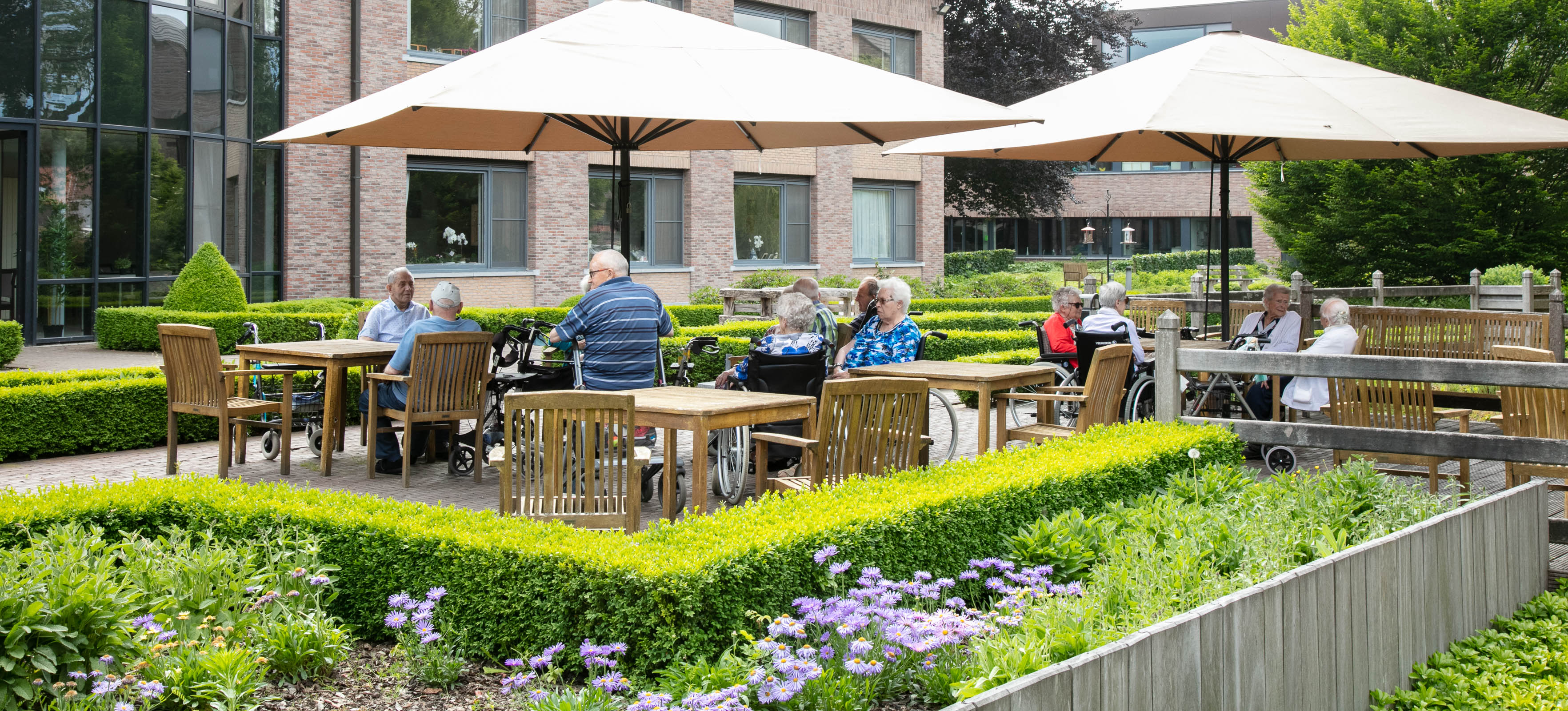 Seniorenzorg Philippus Neri senioren op terras met bloeiende bloemen