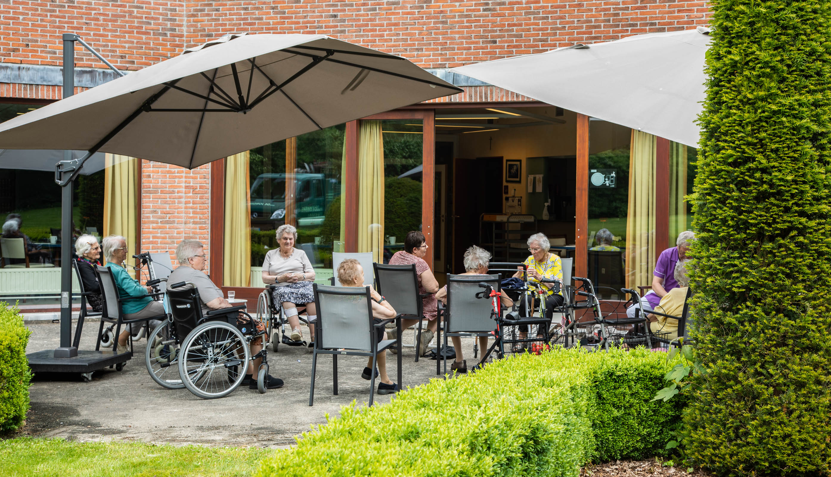 Seniorenzorg Philippus Neri gezellig terras met parasols voor bewoners van Huize Den Dries in Sinaai